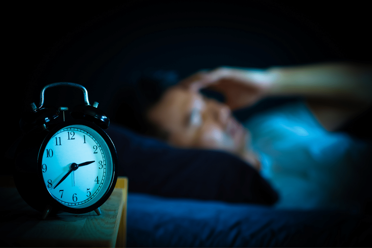 A man woke up with alarm clock beside his bed.