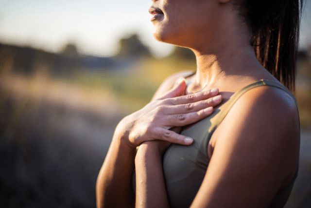 Woman holding hands to chest in a moment of reflection.