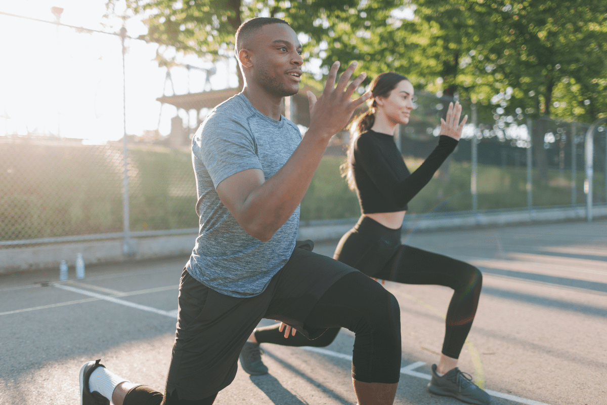 Two people next to each other performing Yoga in sunshine.