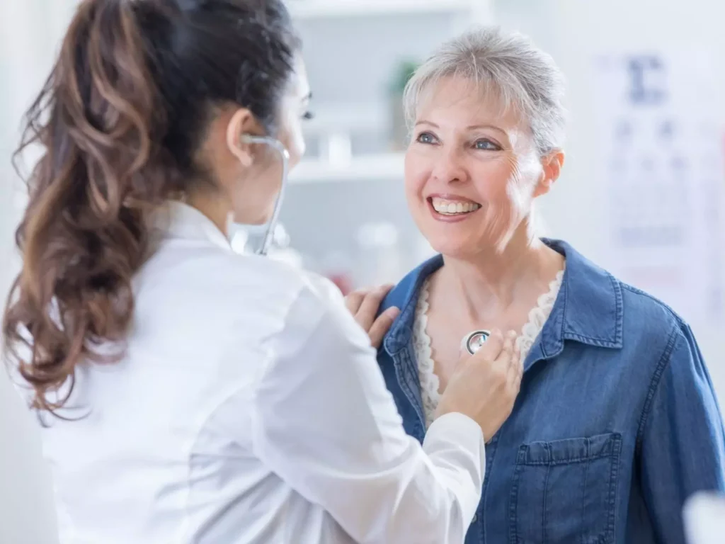 Smiling woman receives a chest exam from female doctor.