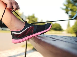 Person tying running shoe on track at sunset.