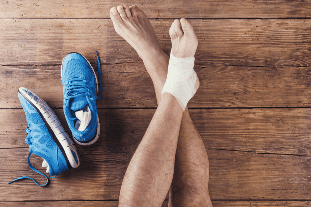 Person with a bandaged ankle next to blue running shoes.
