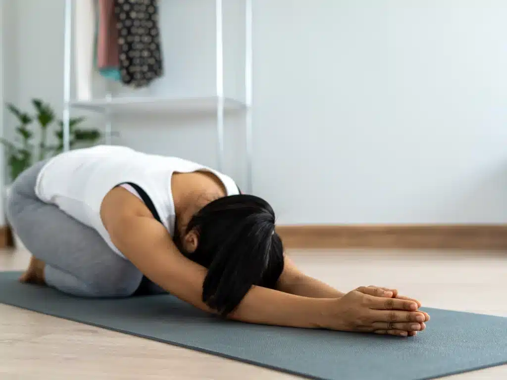 A women performing yoga on mat.